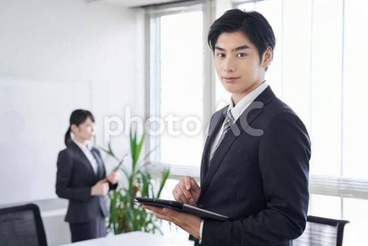 オフィスで笑顔で迎える日本人ビジネスマン ビジネスウーマン,男性,ビジネスマンの写真素材