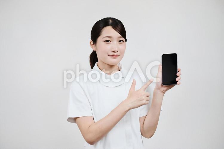 スマートフォンを操作する白衣の女性 予約,問い合わせ,病院の写真素材
