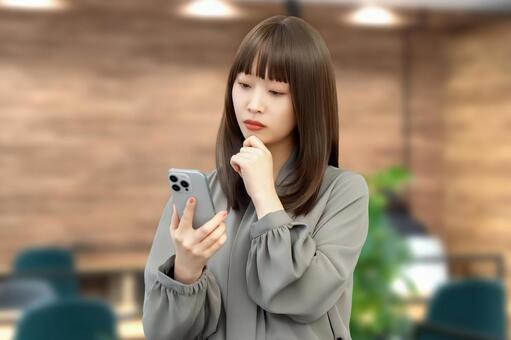 スマホを見て考える女性・ビジネスウーマン 女性,困る,考えるの写真素材