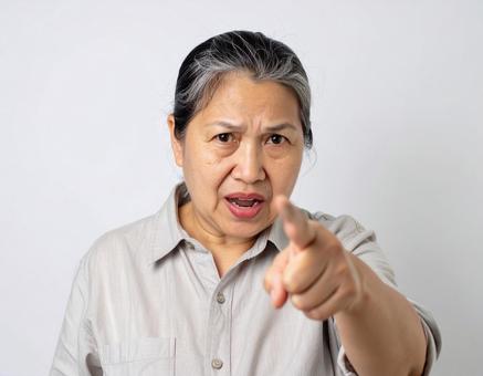 怒りながら指を指して文句を言う初老の女性 怒りながら指を指して文句を言う初老の女性の写真