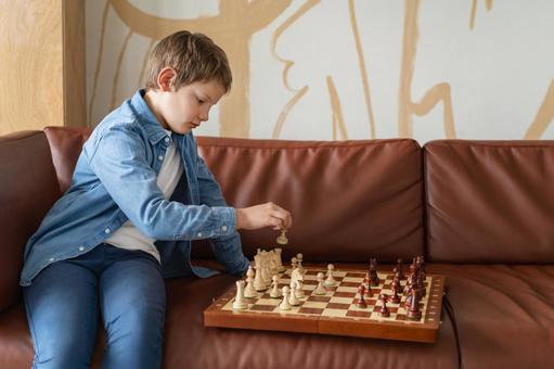 ソファで一人チェスをする男の子 ソファで一人チェスをする男の子の写真