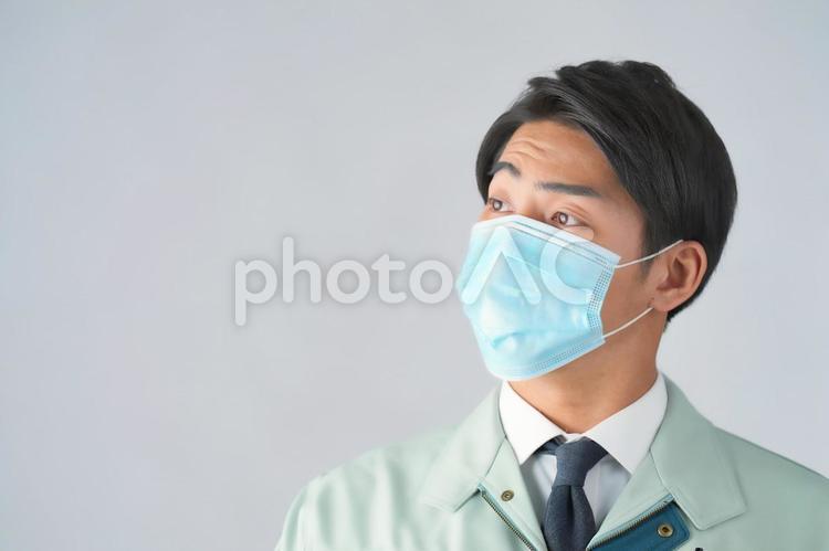 よそ見をするマスクの男性作業員（白背景） 男性,作業員,よそ見の写真素材