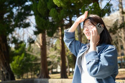 公園で電話をする女性 公園で電話をする女性の写真