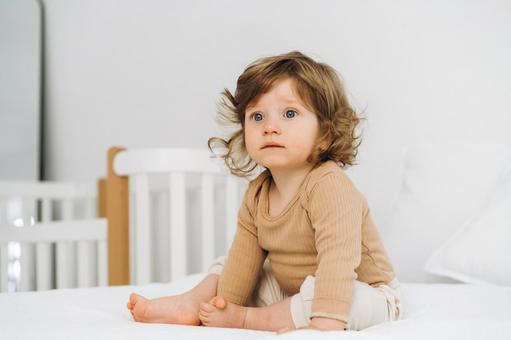 お座りしているベージュの服の子供 お座りしているベージュの服の子供 赤ちゃん,かわいい,お座りの写真素材