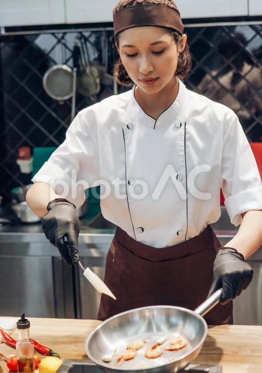 フライパンでエビを調理している女性シェフ キュイジーヌ,キッチン,厨房の写真素材