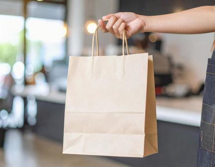 デリバリーの紙袋を持つ手の写真