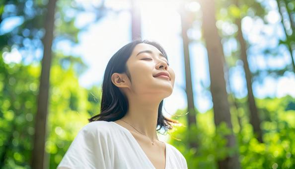 緑の中で目を閉じて深呼吸する日本人女性 緑の中で目を閉じて深呼吸する日本人女性の写真