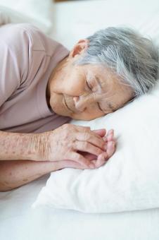枕に手を置き寝ている高齢女性の寝顔 女性,寝る,目を瞑るの写真素材