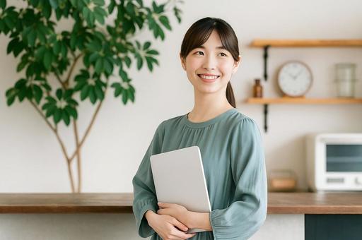 ノートパソコンを軽く抱えて微笑む若い女性 ノートパソコンを軽く抱えて微笑む若い女性の写真