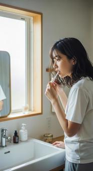 朝の洗面所で歯磨きをする若い女性 朝の洗面所で歯磨きをする若い女性の写真