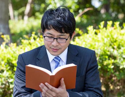 屋外で読書しているサラリーマン 屋外で読書しているサラリーマンの写真