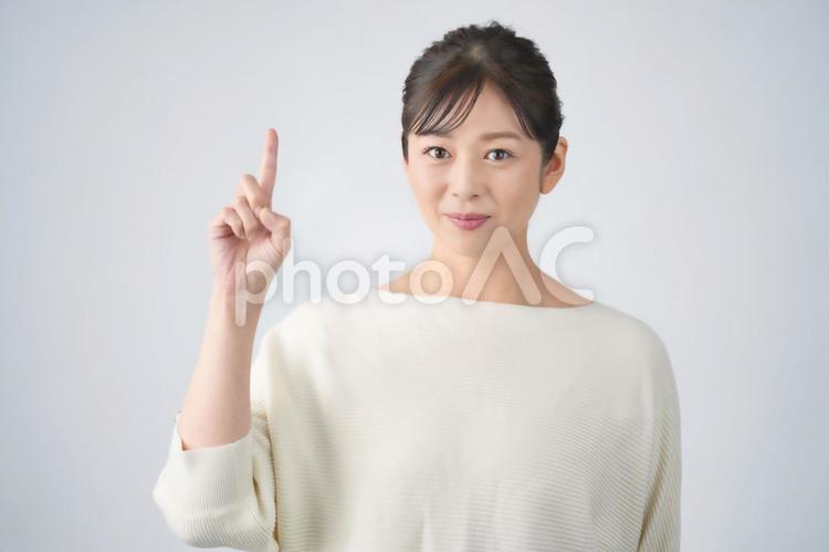 指を1本立ててカメラ目線の女性(白背景) 女性,主婦,カメラ目線の写真素材