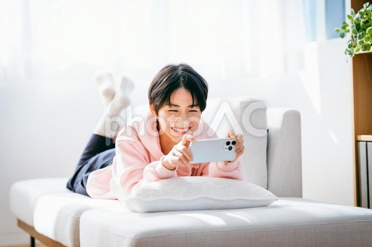 部屋でスマホを操作する若い女性 女性,スマホ,スマートフォンの写真素材
