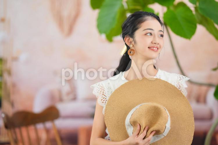 麦わら帽子を持ち横を見る女性 女性,麦わら帽子,持つの写真素材