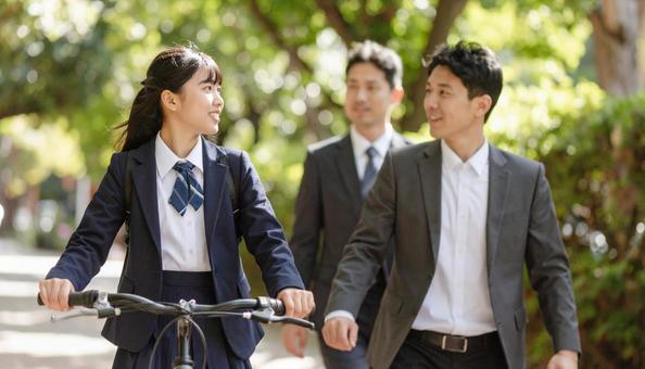 自転車に乗る制服の子供と歩くお父さん 自転車に乗る制服の子供と歩くお父さんの写真