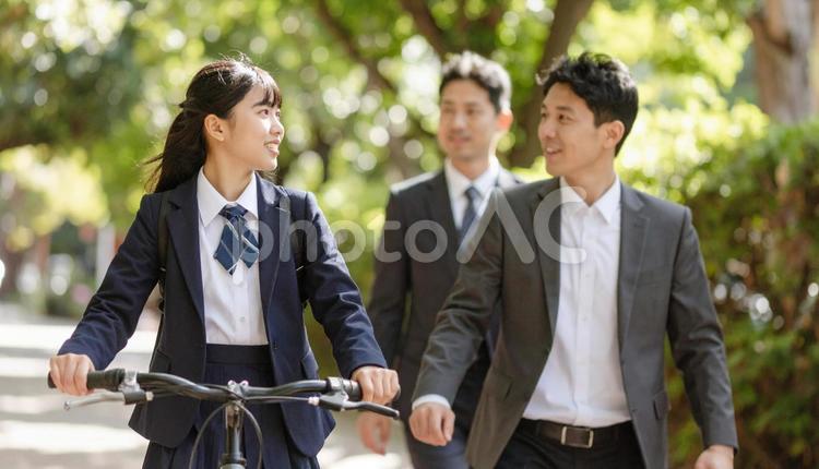 自転車に乗る制服の子供と歩くお父さん 子供,両親,自転車の写真素材