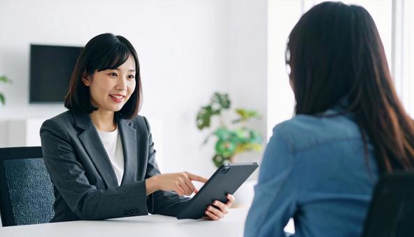 タブレットを使って説明する女性営業マン タブレットを使って説明する女性営業マンの写真