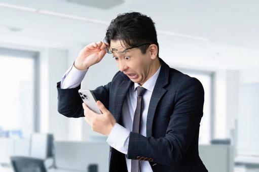 スマホを見て驚く男性ビジネスマン 男性,スマホ,スマートフォンの写真素材