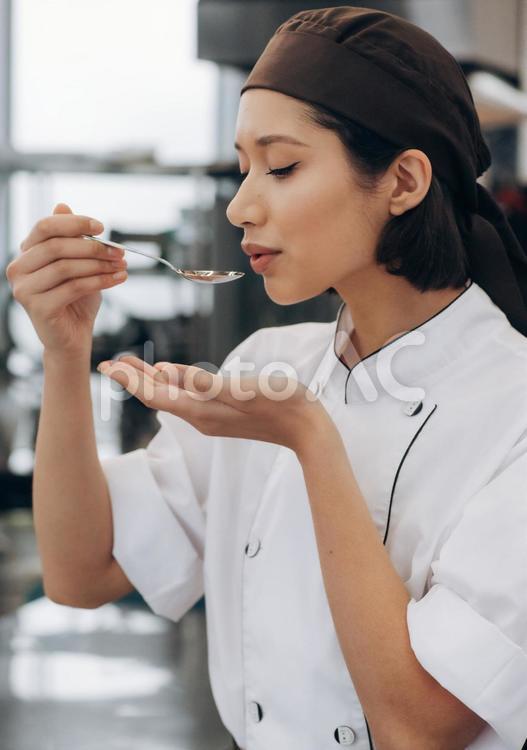 スプーンで味見をする女性シェフ キュイジーヌ,キッチン,厨房の写真素材