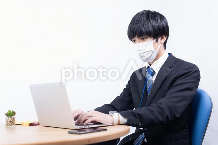 マスクをつけてパソコンにタイピングする日本人男性会社員 白バック,白背景,スーツの写真素材