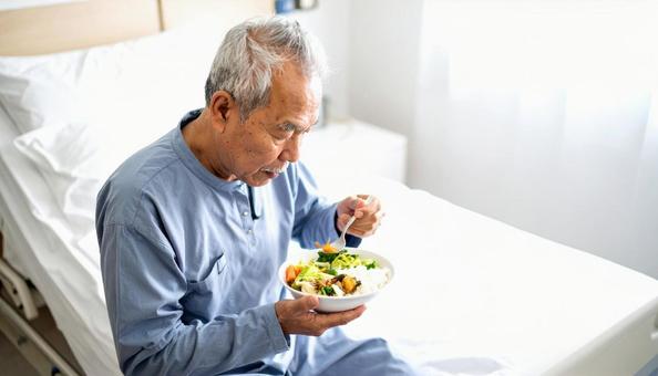 端座位で食事をするシニア男性の患者 端座位で食事をするシニア男性の患者の写真