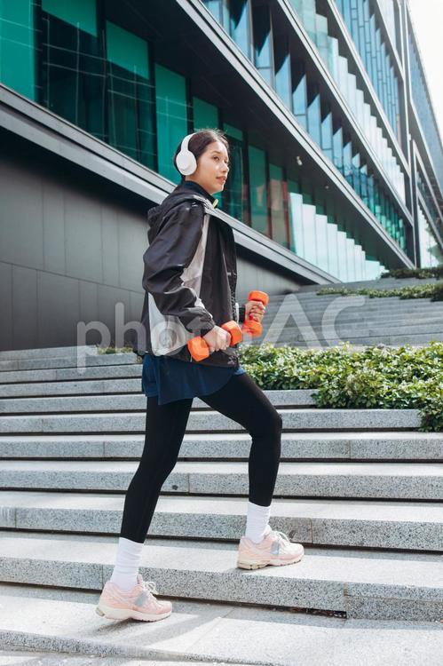 ダンベルを持って階段を歩く女性 女性,ヘッドフォン,筋トレの写真素材