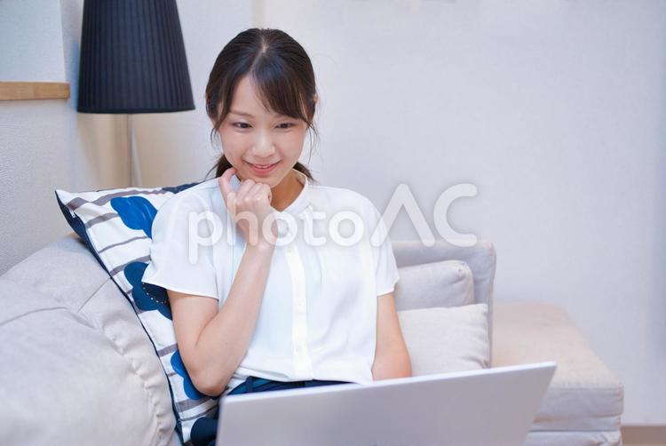 ソファーでノートパソコンを楽しむ女性 女性,若い,人物の写真素材