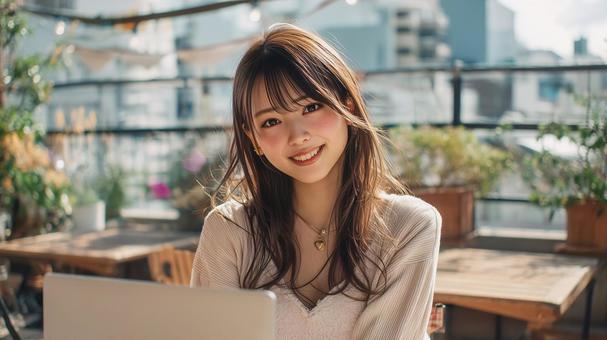 緑豊かなカフェでノートPCを使用する女性 緑豊かなカフェでノートPCを使用する女性の写真