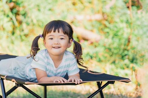 キャンプ場でコットに寝転ぶ女の子・子供 キャンプ,子供,笑顔の写真素材