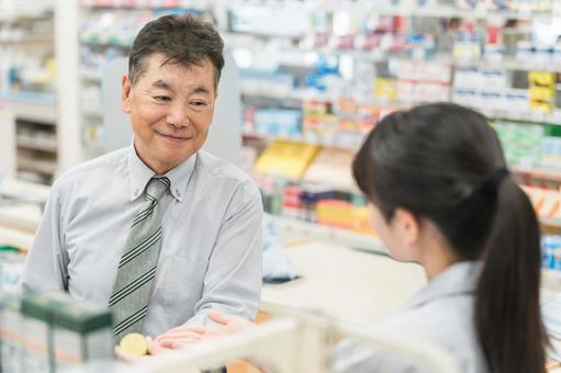 薬局で薬剤師から服薬指導を受ける男性 薬局で薬剤師から服薬指導を受ける男性 服薬指導,ドラッグストア,薬局の写真素材