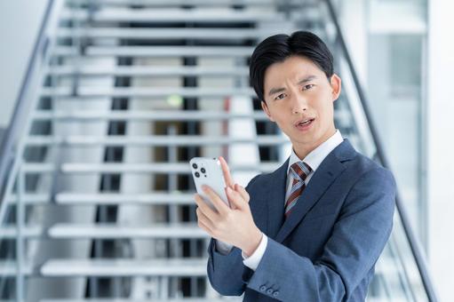 スマホで悩む若いビジネスマン スマホで悩む若いビジネスマンの写真