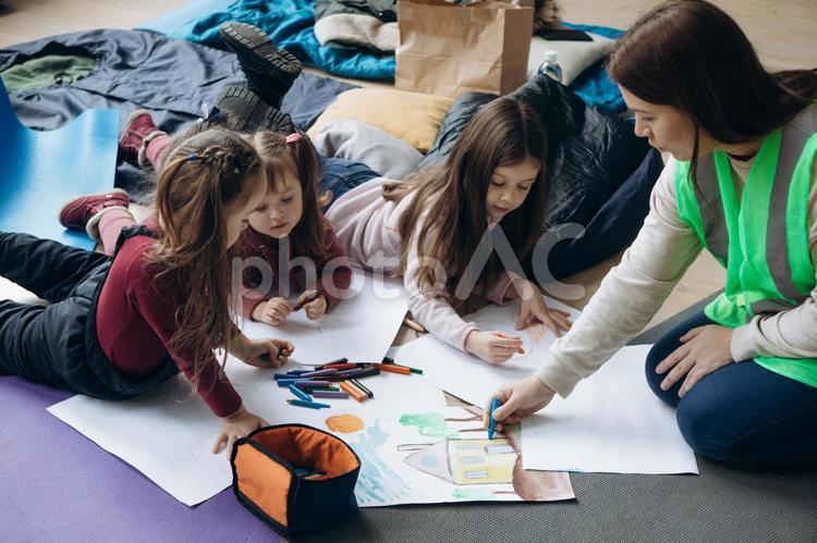 寝転んでお絵描きする女の子とボランティアの女性 女性,女の子,人物の写真素材