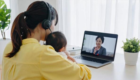 赤ん坊を抱きながらビデオ通話で話す女性 赤ん坊を抱きながらビデオ通話で話す女性の写真