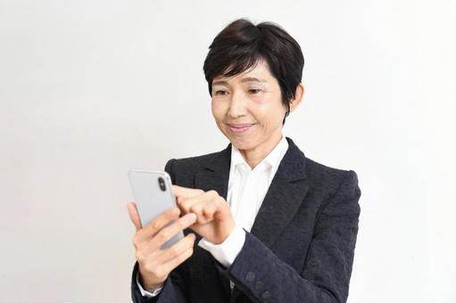 スーツ姿のアジア人シニア女性がスマホ操作 女性,スマホ,スマートフォンの写真素材