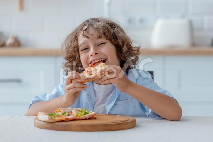 ピザを食べて微笑む男の子１ 男の子,ピザ,持つの写真素材