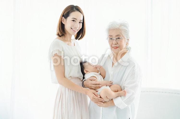 赤ちゃんを抱っこするシニア女性とお母さん  孫,おばあちゃん,親子の写真素材