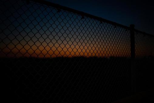 フェンス越しの夕焼けグラデーション フェンス,金網,夕焼けの写真素材