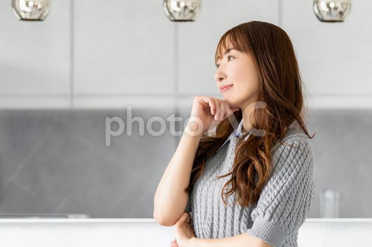 キッチンのカウンターで考える笑顔の女性 女性,笑顔,キッチンの写真素材