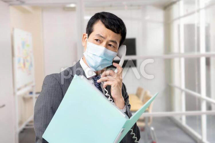 オフィスでマスクをして電話する会社員 マスク,会社員,男性の写真素材