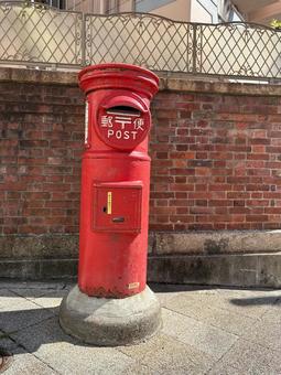 レンガ壁と赤い丸型ポスト 郵便ポスト,丸型ポスト,赤いポストの写真素材