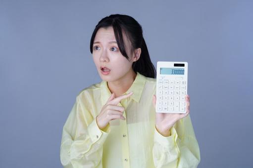 電卓を指さす黄色い服を着た女性の写真
