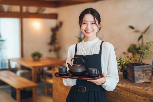 笑顔でお茶を運ぶウェイトレス 笑顔でお茶を運ぶウェイトレスの写真