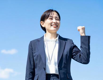 青空の下ガッツポーズする女性社員 青空の下ガッツポーズする女性社員の写真