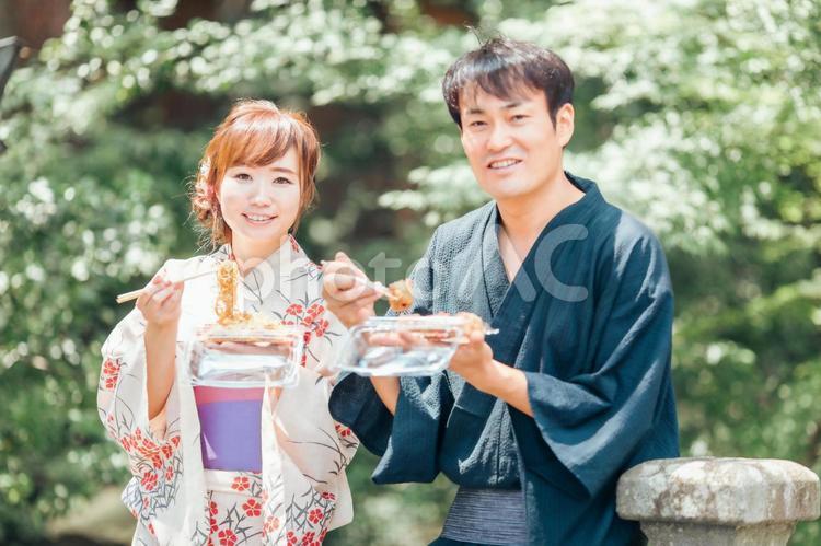 夏祭りにきて焼きそばやたこ焼きを食べる男女 浴衣,夏祭り,夫婦の写真素材