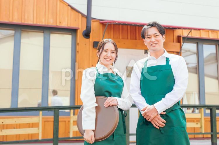 お店の前に立つエプロン姿の男女 カフェ,飲食店,ウェイトレスの写真素材