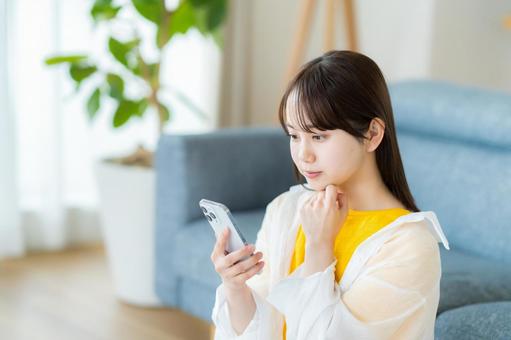 スマホを見て考える若い女性 スマホを見て考える若い女性 スマホ,考える,悩むの写真素材