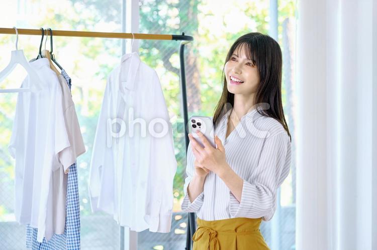 スマホを持つ主婦　女性　洋服　ハンガー 女性,主婦,スマホの写真素材