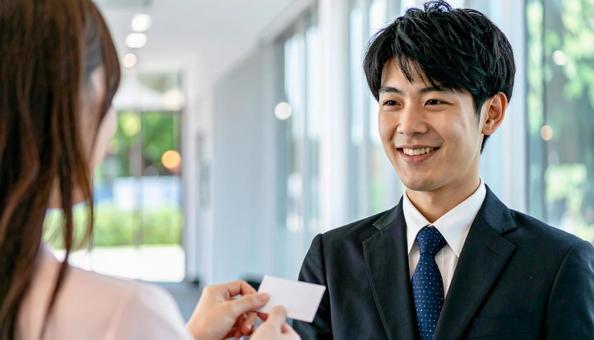 笑顔で名刺を差し出す男性社員の写真