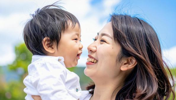 青空の下、子供を抱っこする母親 青空の下、子供を抱っこする母親の写真