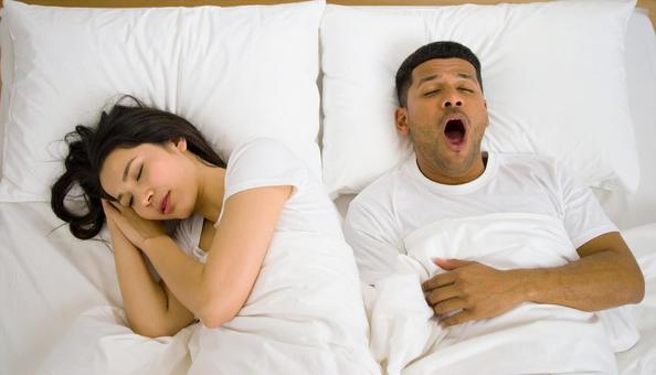 ベッドで夫のいびきで睡眠不足の妻 ベッドで夫のいびきで睡眠不足の妻の写真